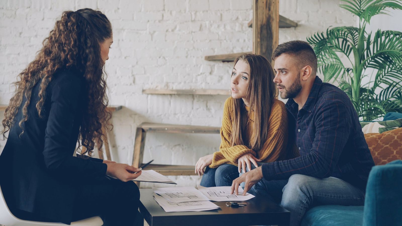 A consultant reviews plan documents with a business-owner couple in a bright office